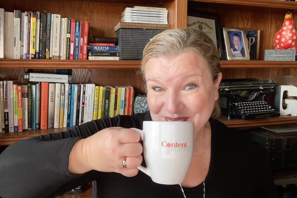 Kenna Griffin with a mug of coffee in front of her bookshelf