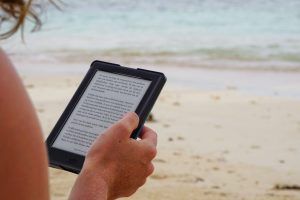 woman holding a Kindle on the beach