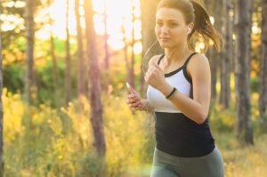 A woman running while holding an iPhone and listening to something on earbuds